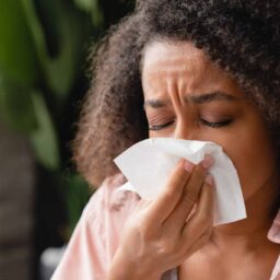 Woman with a sinus infection blowing her nose.