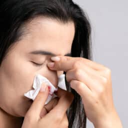 Woman with nosebleed holds nose