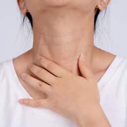 Woman holds hand to neck