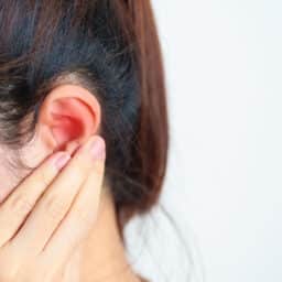 Woman holds hand behind ear