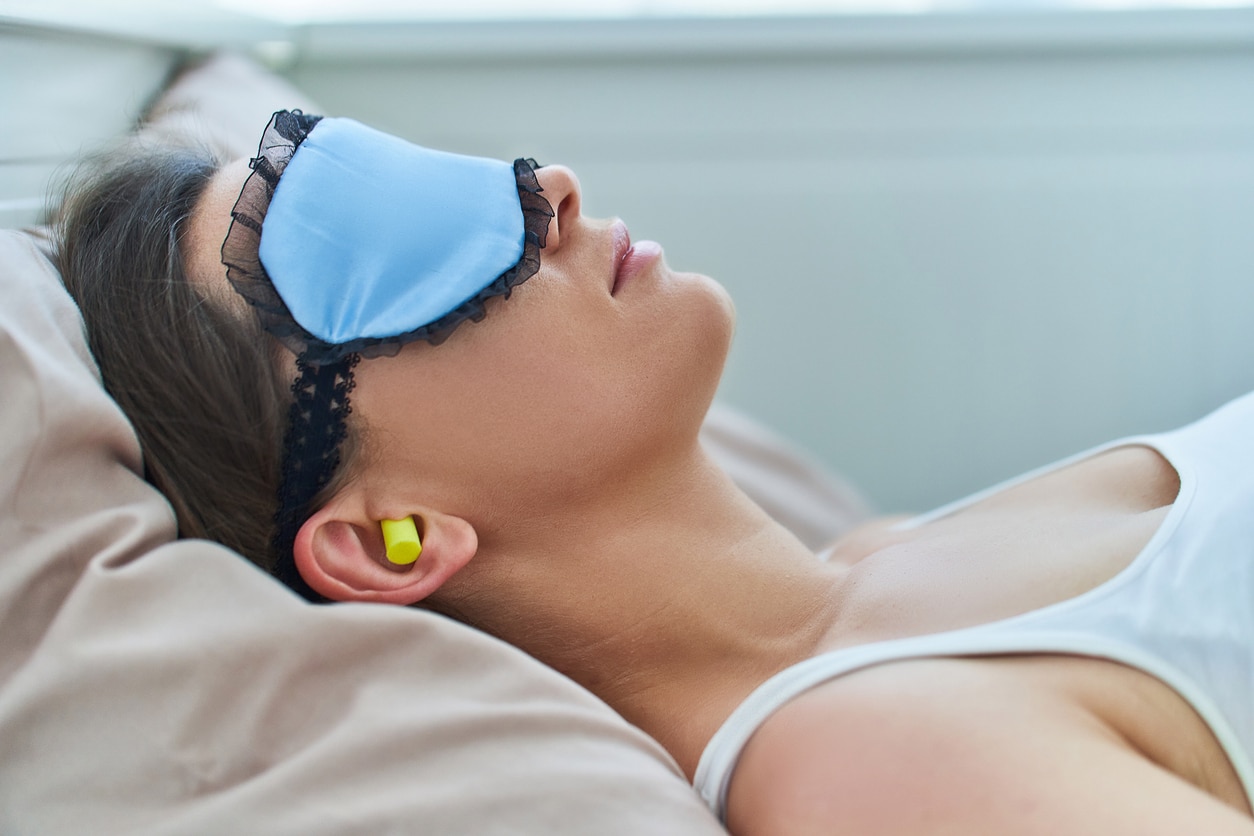 Woman wearing earplugs and eye mask for better sleeping.