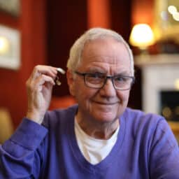 Man shows off his hearing aid in a lovely living room before Thanksgiving dinner.