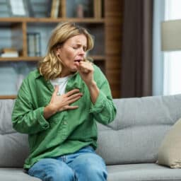 Woman coughing at home in her living room.