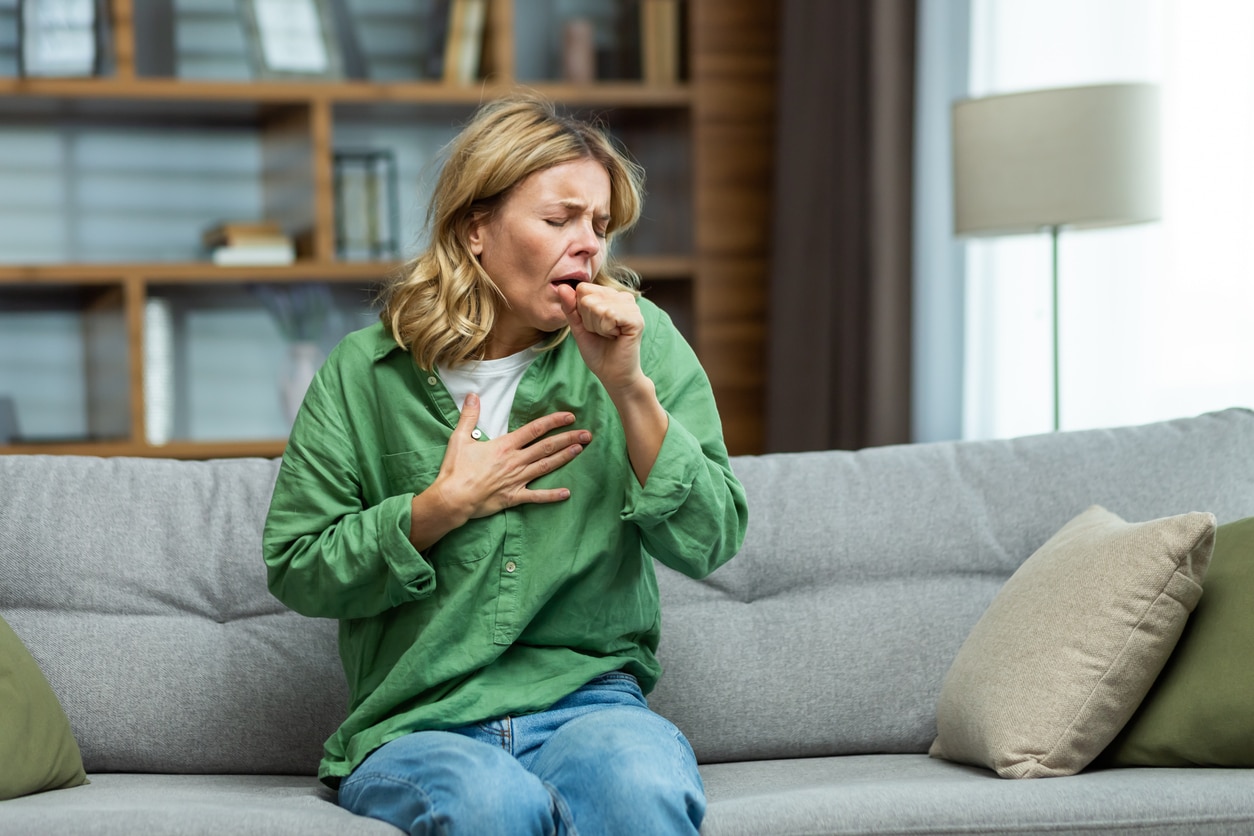 Woman coughing at home in her living room.
