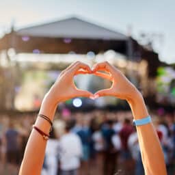 Concertgoer makes a hand heart gesture at an outdoor music event.