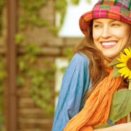 Happy summer! A trendy woman holds a sunflower on a hot day.