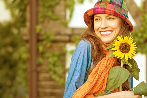 Happy summer! A trendy woman holds a sunflower on a hot day.
